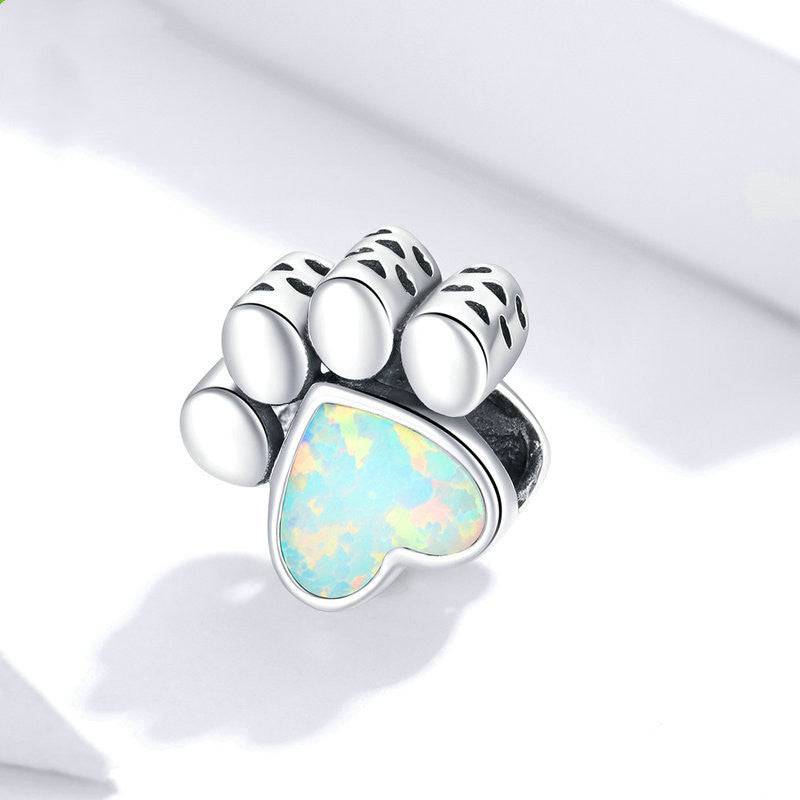 Dog paw charm with opal heart on white background