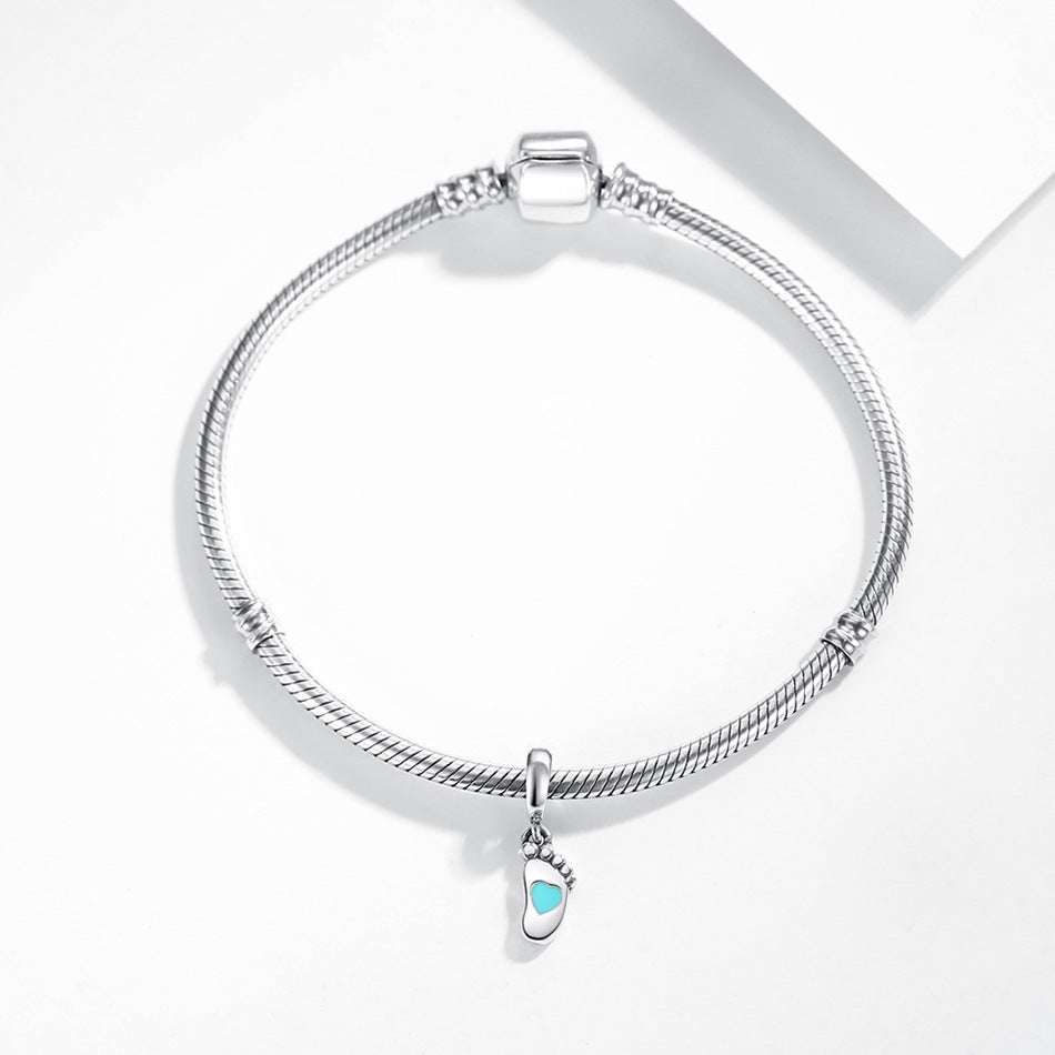 Elegant sterling silver bracelet with a baby footprint charm, showcasing a turquoise heart accent. A timeless keepsake for new parents.