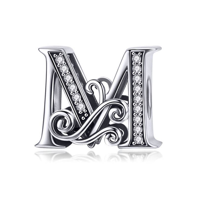 Ornate letter M charm with swirl design