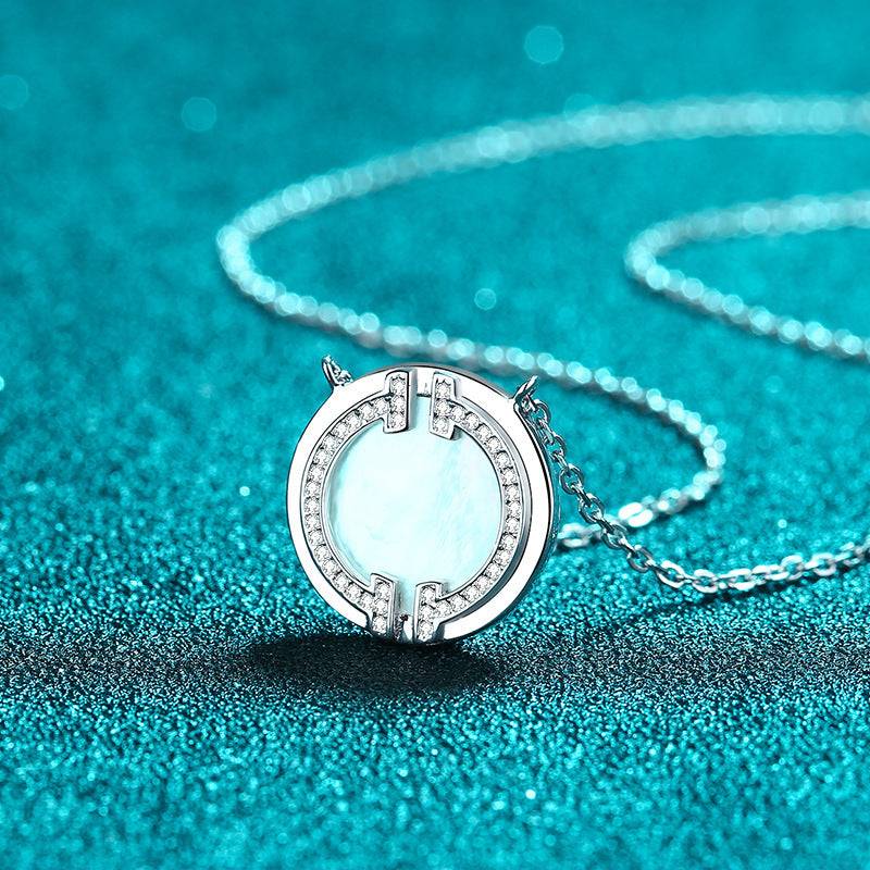 Circular moissanite necklace displayed on a glittering turquoise background, highlighting its intricate design and brilliance.