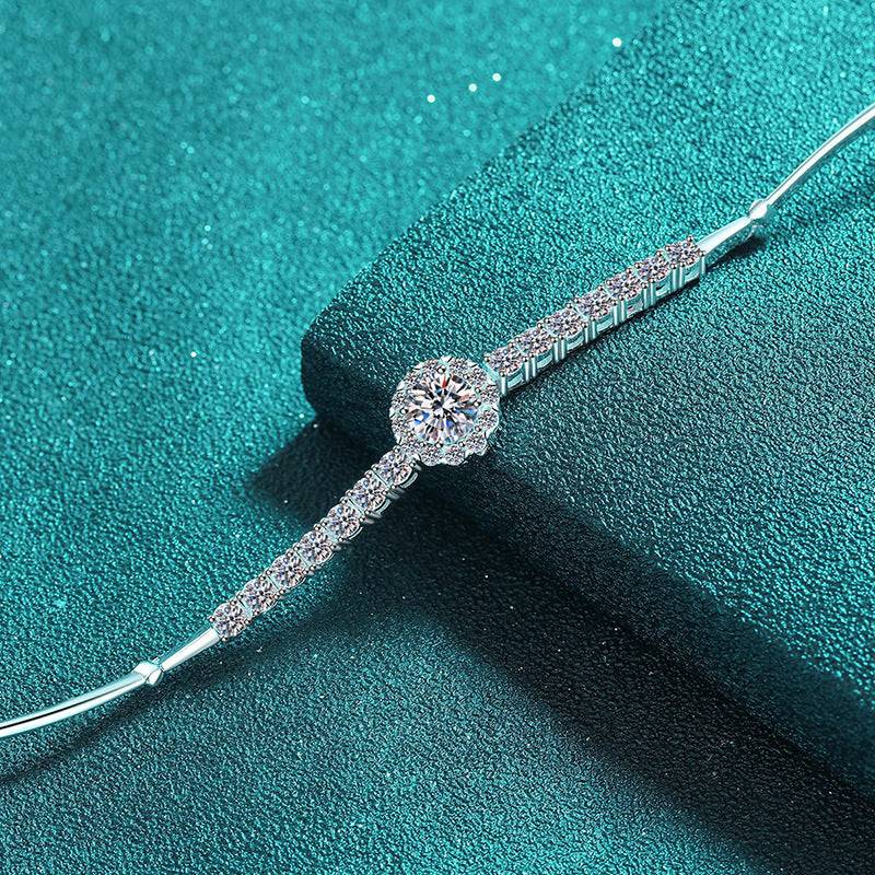 Close-up of the Silver Moissanite Bangle showcasing intricate moissanite detailing and a sleek silver design on a textured teal background.