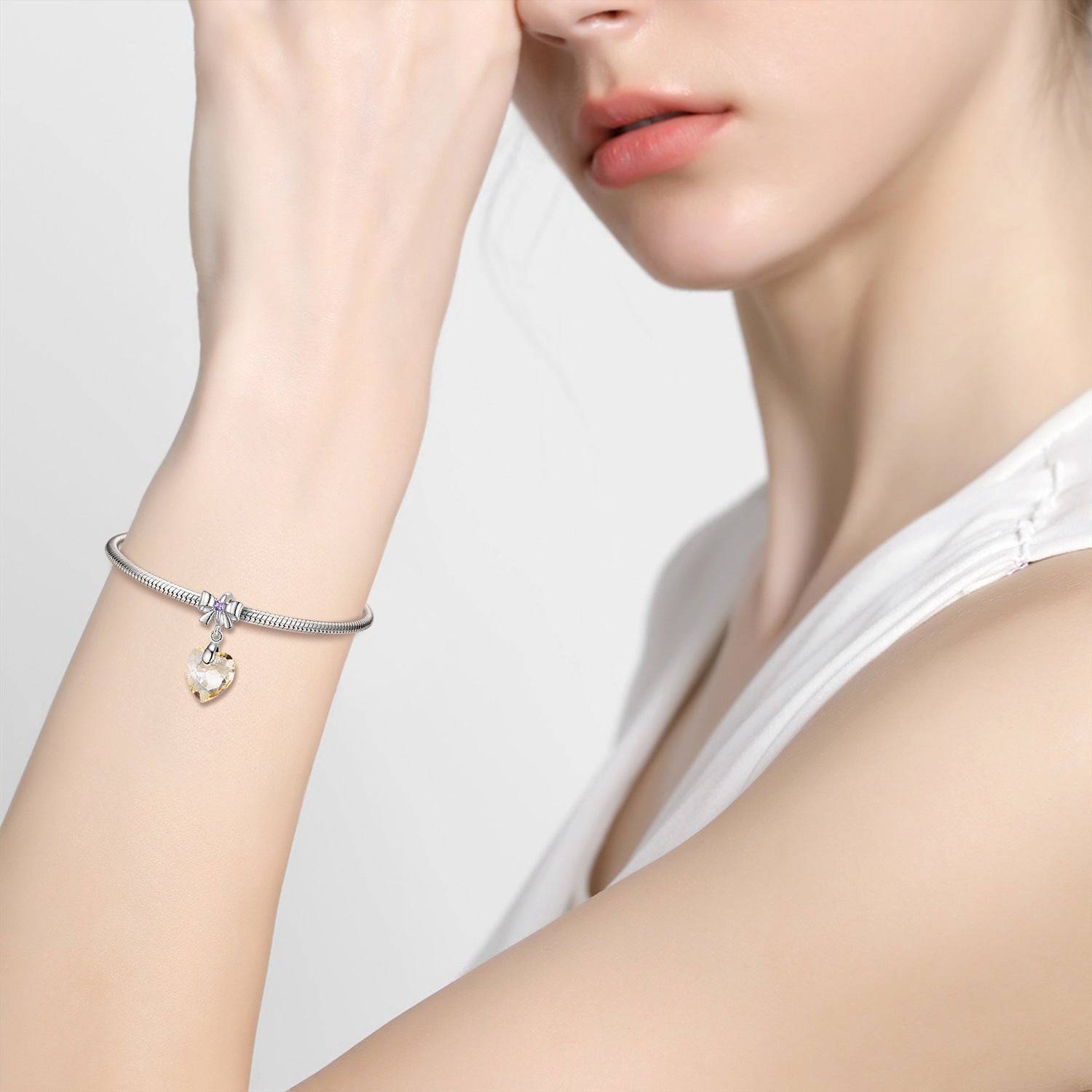 Model wearing a Golden Crystal Charm on a silver bracelet, showcasing its luxurious shine and stylish appeal. Perfect for any occasion.